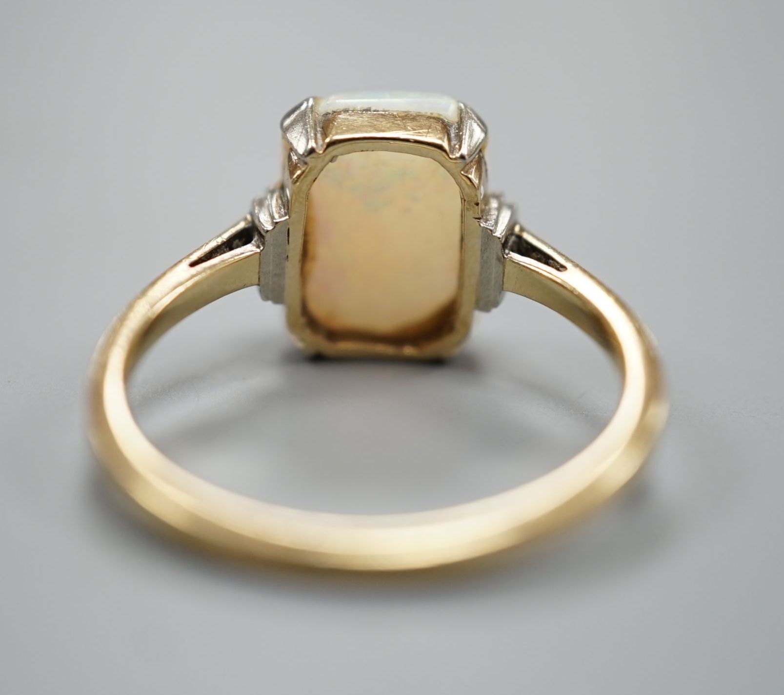 A 9ct and 'emerald' cut white opal set ring, size R, gross weight 3.2 grams.